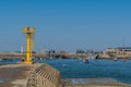 Yellow lighthouse on concrete pier overlooking Jeongok port