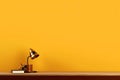 Yellow lighting retro desk lamp on old wood table with space of rough cement wall in vintage color tone Royalty Free Stock Photo