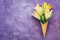 Yellow lilies in a waffle cone on abstract purple background. Beautiful spring creative background, place for text