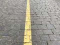 Yellow line in the center of grey brick of road. Concrete footpath arrangement.