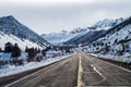 Two lane paved road ascending into snowy mountains