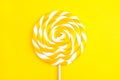 Yellow lollipop in the shape of a circle on a yellow background.