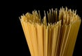 Yellow long spaghetti on black background. Thin pasta arranged in rows. Yellow italian pasta. Long spaghetti. Raw spaghetti