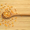 Yellow maize corn kernels ready for making popcorn, on bamboo cutting board and in wooden spoon Royalty Free Stock Photo