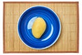 Yellow mango on a blue plate on a cane serving mat