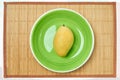 Yellow mango on a green plate on a cane place mat