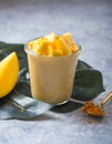 Yellow mango yogurt or smoothie on grey background. Turmeric Lassie or lassi in glass