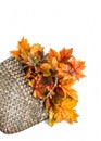 Yellow maple autumn leaves in a wicker straw basket on a white background with copy space, top view