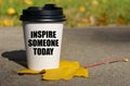 On a yellow maple leaf there is a cup of coffee on which is written - inspire someone today Royalty Free Stock Photo