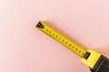 Yellow measuring tape on a pink background. Close-up