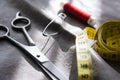 Yellow measuring tape, scissors and reel of red thread on gray fabric Royalty Free Stock Photo