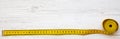 Yellow measuring tape on white wooden table, top view. From above, flat lay. Royalty Free Stock Photo