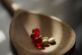 Yellow medical pills and red vitamins a wooden spoon, closeup, side view Royalty Free Stock Photo