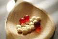 Yellow medical pills and red vitamins a wooden spoon, closeup on the table, side view Royalty Free Stock Photo