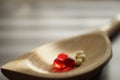 Yellow medical pills and red vitamins a wooden spoon, closeup on the table, side view Royalty Free Stock Photo
