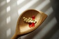 Yellow medical pills and red vitamins in a wooden spoon. Top view on the chrome sunny table Royalty Free Stock Photo