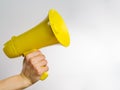 Yellow megaphone in a man`s hand on a white background. Minimalism. There is free space to insert. Symbol of false information,