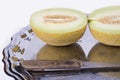 Yellow melon or cantaloupe on the old tray on the white background with knife cut in half in detail Royalty Free Stock Photo