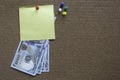 A yellow memo note with a dollar bill and colorful push pin on a notice cork board. Copy space for text ,logo Royalty Free Stock Photo