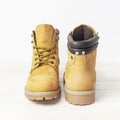 Yellow men`s work boots from natural nubuck leather on wooden white background. Trendy casual shoes, youth style. Concept of Royalty Free Stock Photo