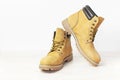 Yellow men`s work boots from natural nubuck leather on wooden white background. Trendy casual shoes, youth style. Concept of