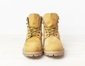 Yellow men`s work boots from natural nubuck leather on wooden white background. Trendy casual shoes, youth style. Concept of Royalty Free Stock Photo