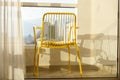 Yellow Metal Chair on Balcony with Serene View, Embracing Summer Bliss.