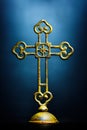 Yellow metal cross close-up with a moody blue background