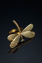 Yellow metal dragonfly ring on black glass with reflection Royalty Free Stock Photo