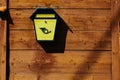 Yellow metal mailbox on a wooden wall