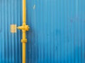 Yellow pipe with valve on the blue wall background Royalty Free Stock Photo