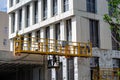 Yellow metal platform to lift workers to produce facade work Royalty Free Stock Photo