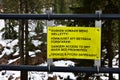 Yellow metal warning signboard against winter forest view background