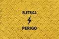 Yellow metallic surface with portuguese words that mean ELETRICITY and DANGER