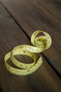 A yellow meter lies on a wooden table. Measuring tape in yellow color. Royalty Free Stock Photo