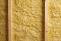 Yellow mineral wool filling in unfinished wall used as isolation between wooden beams