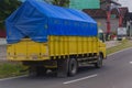 Yellow mitsubishi canter truck driving fast on the road during rainy day