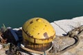 A yellow mooring bollard with a mooring rope on the harbor pier Italy, Europe Royalty Free Stock Photo