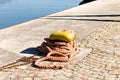 A yellow mooring bollard with a mooring rope on the harbor pier Italy, Europe Royalty Free Stock Photo