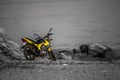 Yellow motorcycle with blue eyes on the mirrors against the background of the black and white sea, stones and shore