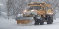 Yellow municipal snow plow plowing during a blizzrd