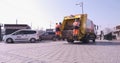 Yellow municipality waste collection vehicle moves after two municipality workers garbage man taking garbage in public avenue