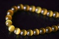 Yellow necklace of stone beads cat`s eye on a dark background Royalty Free Stock Photo