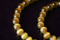 Yellow necklace of stone beads cat`s eye on a dark background Royalty Free Stock Photo