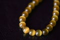 Yellow necklace of stone beads cat`s eye on a dark background Royalty Free Stock Photo