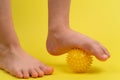 yellow needle ball for massage and physical therapy on a yellow background with a child& x27;s foot, the concept of Royalty Free Stock Photo
