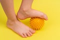 yellow needle ball for massage and physical therapy on a yellow background with a child& x27;s foot, the concept of Royalty Free Stock Photo