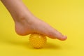 yellow needle ball for massage and physical therapy on a yellow background with a child& x27;s foot, the concept of Royalty Free Stock Photo