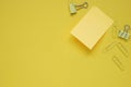 yellow note pad stick on yellow paper against group of yellow binders clips, top view, flat lay