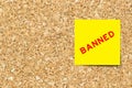 Yellow note paper with word banned on cork board Royalty Free Stock Photo